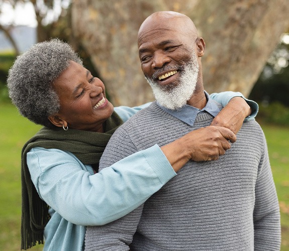 Older couple smiling while wearing dentures