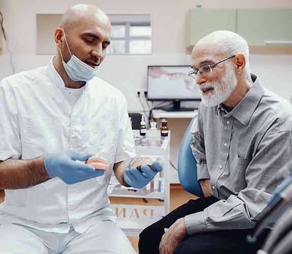 Dentist and male patient discussing implant dentures