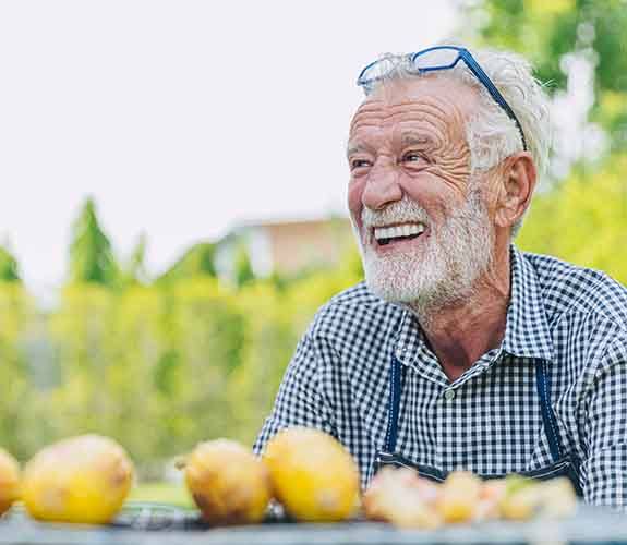 Older man smiling with new implant dentures