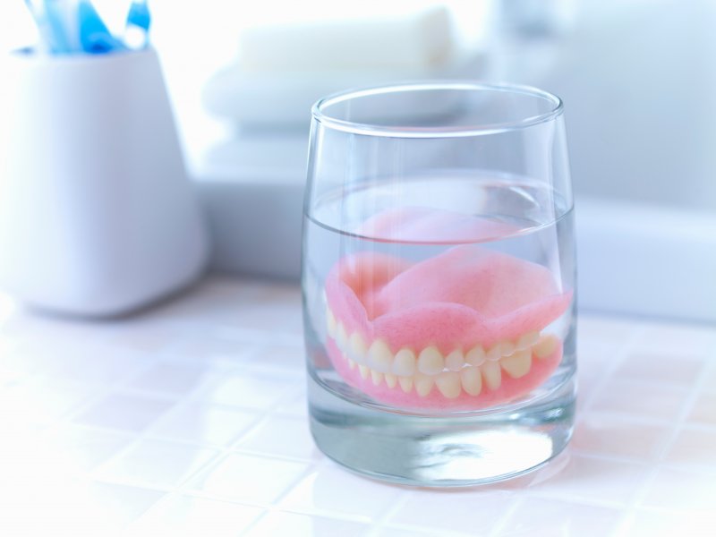 full set of dentures soaking in a glass of water  